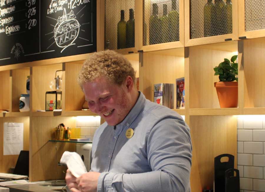A man smiling as he works behind a bar