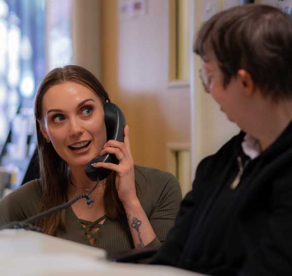 A lady on the phone sits next to a young person with special educational needs