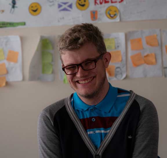 a youn man with glasses laughing